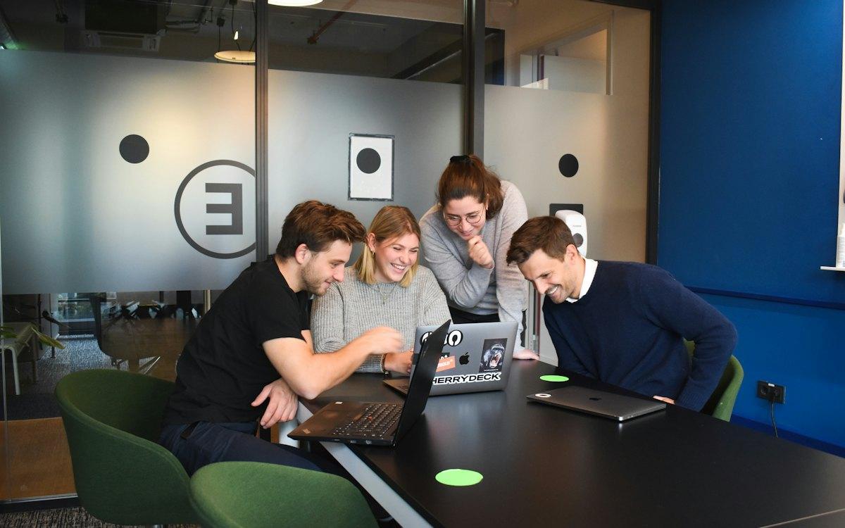 Equipe reunida em volta de um notebook analisando dados